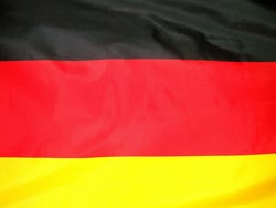 La imagen muestra la bandera alemana desde muy cerca. Se aprecian los colores negro, rojo y dorado típicos de Alemania.